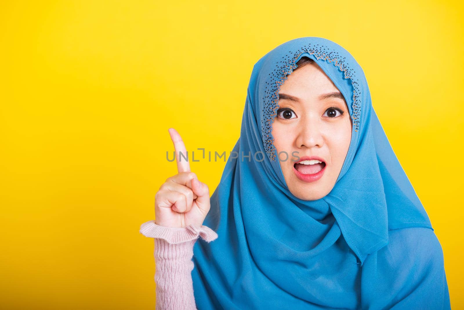 Asian Muslim Arab woman Islam wear hijab smile she positive expression pointing with finger up by Sorapop