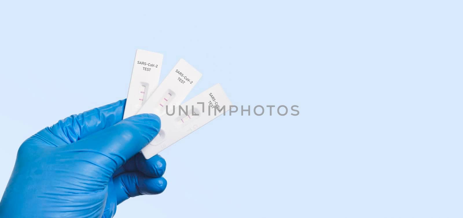 The doctor showing Covid-19 positive test result with SARS CoV-2 Rapid antigen test kit (ATK), isolated on blue background with copy space,Coronavirus infectious protective concept