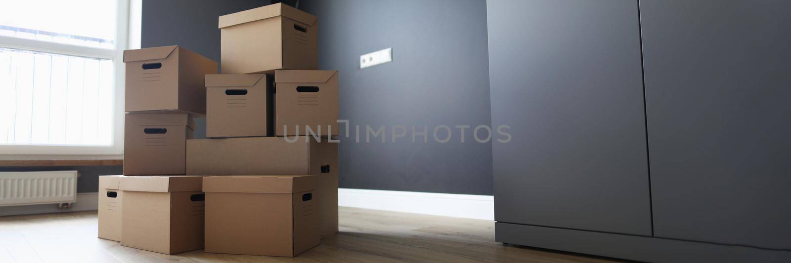 Close-up of boxes with belongings in empty room, movement or delivery. Cardboard boxes with goods, fresh interior design. Moving day, renovation, new place for living concept