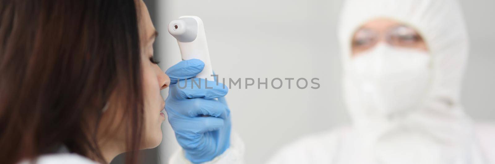 Close-up of disease control expert use infrared thermometer equipment to check temperature of patient. Measure fever of ill woman. Coronavirus epidemic, quarantine, pandemic concept