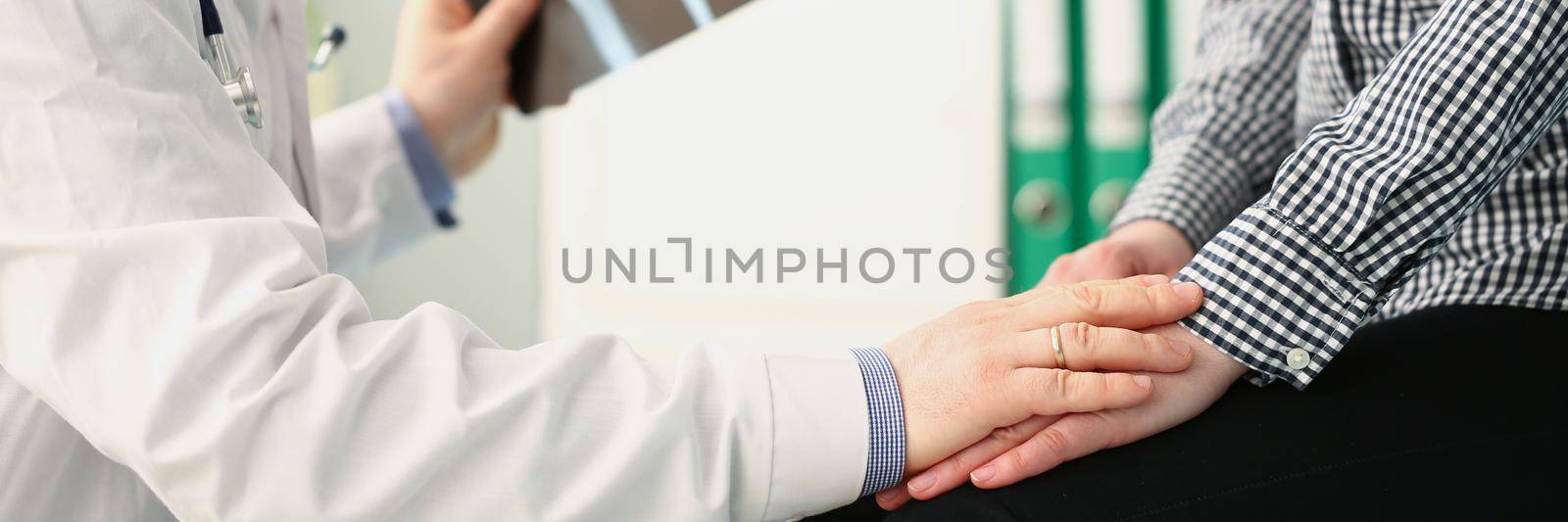 Close-up of medical worker support female patient holding x ray result. Doctor in medical gown hold hand on clients hand. Bad news, illness, medicine, healthcare concept. Blurred background