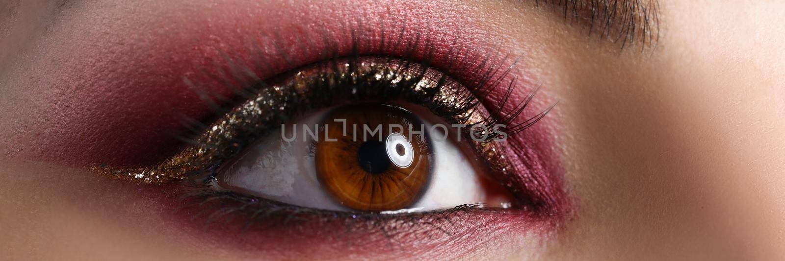 Close-up of creative makeup on womans face, autumn colours. Macro shot of bright eye shadow for new year or birthday celebration. Mua, beauty, makeup, art concept