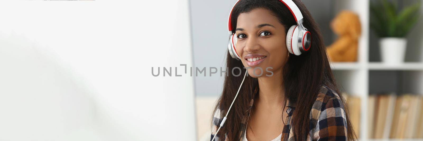Portrait of pretty young office worker in headset, making notes, search information online. Student in university, prepare for exam, learn new material. Job, uni, study concept. Blurred background