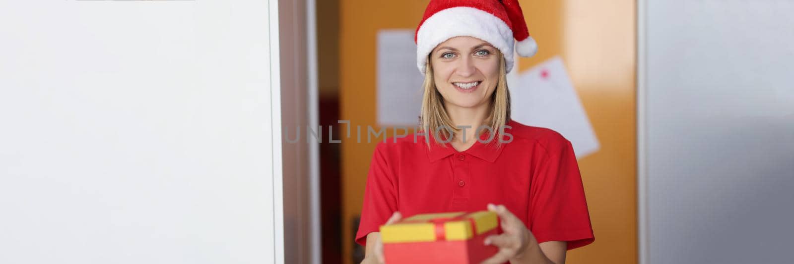 Portrait of woman in festive new year hat delivering parcel to customer, smiling positive worker in special uniform, fast deliver to door. Worldwide shipping, delivery service concept