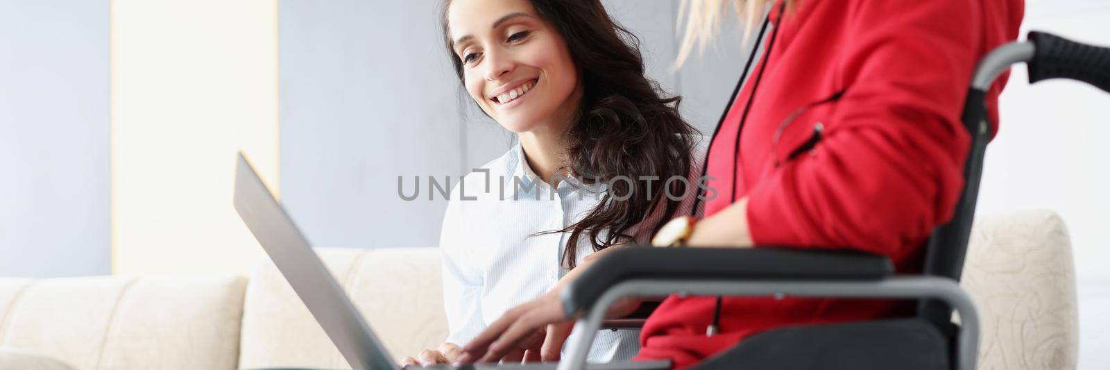 Portrait of sisters spend time together watching fun show on laptop, woman in wheelchair hold device on lap. Disabled people, family, sisterhood, pastime, visit concept