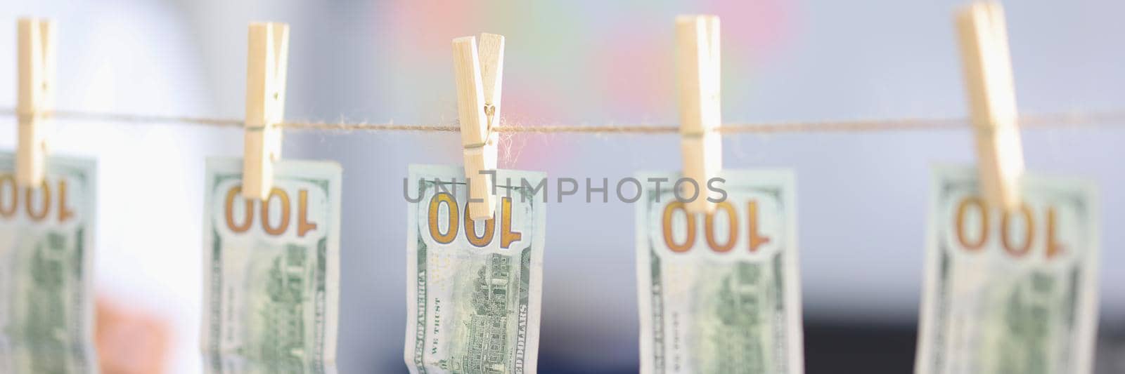 Close-up of banknotes dry on rope, money laundering, dirty cash, washed paper bills. Cash hang out on string. Economy, finance, illegal business, banking, collect, saveup concept. Blurred background