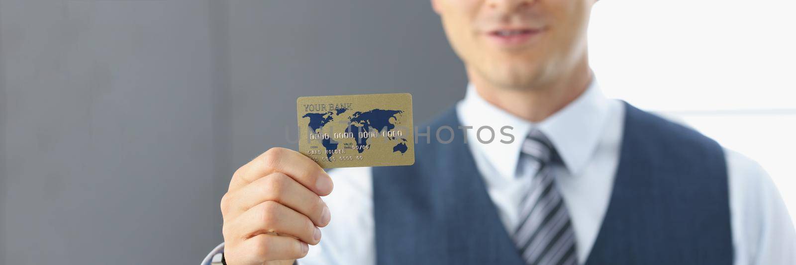 Portrait of smiling handsome businessman standing with credit card, successful worker in classic suit. Achievement, career, wealth, success, banking, opportunity concept