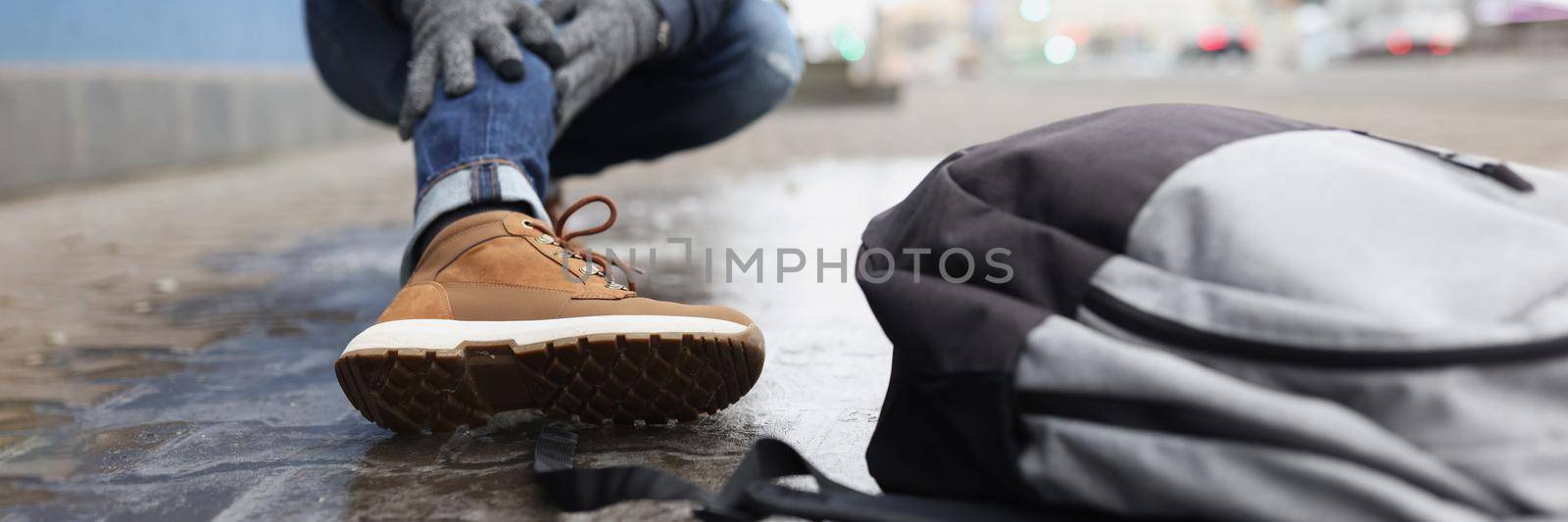 Low angle of man hit leg, broken bone, slippery ground in winter, need help. Person fell on asphalt, backpack on floor. Damage, winter, health, accident, emergency concept