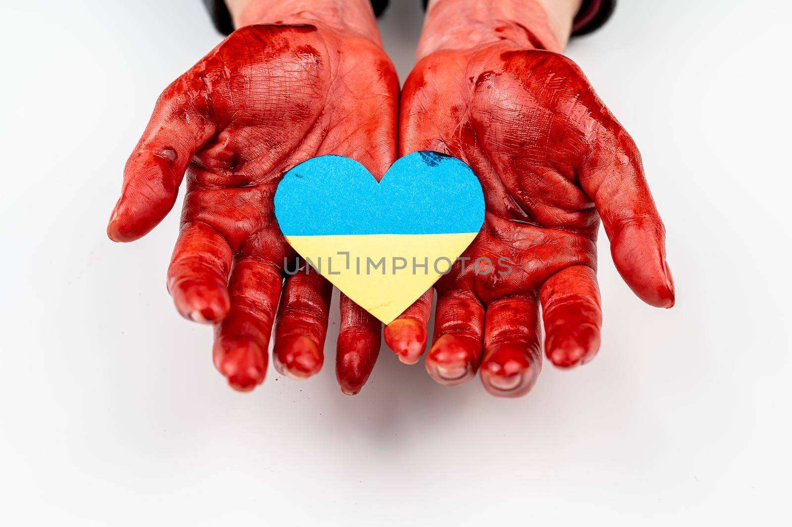 Woman with hands covered in blood holding a heart with the flag of ukraine on a white background