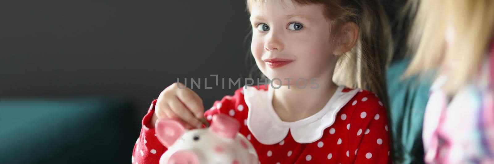 Portrait of cute little child putting coin into piggy bank. Mother teach daughter to save up, save to buy toy or sweets. Childhood, saving up, investment, money, finance concept