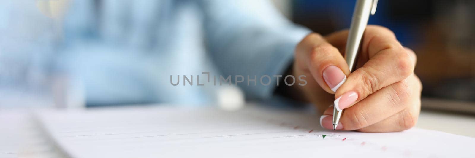 Close-up of female hand holding pen and putting green check on white paper. Application form for personal information. Red crosses and black lines on sheet. Hiring concept. Blurred background