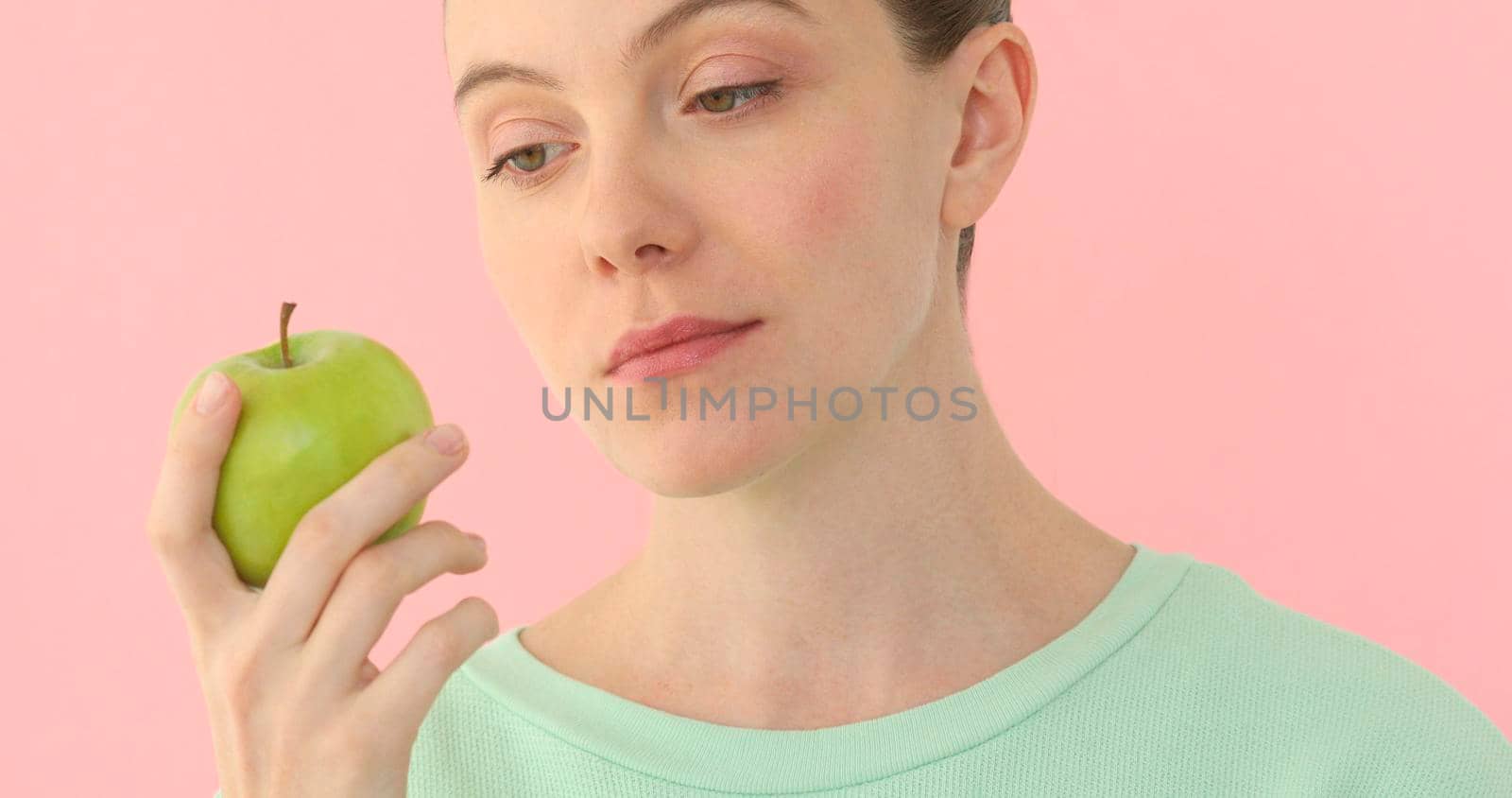 Woman holds green apple enjoys looking at fruit