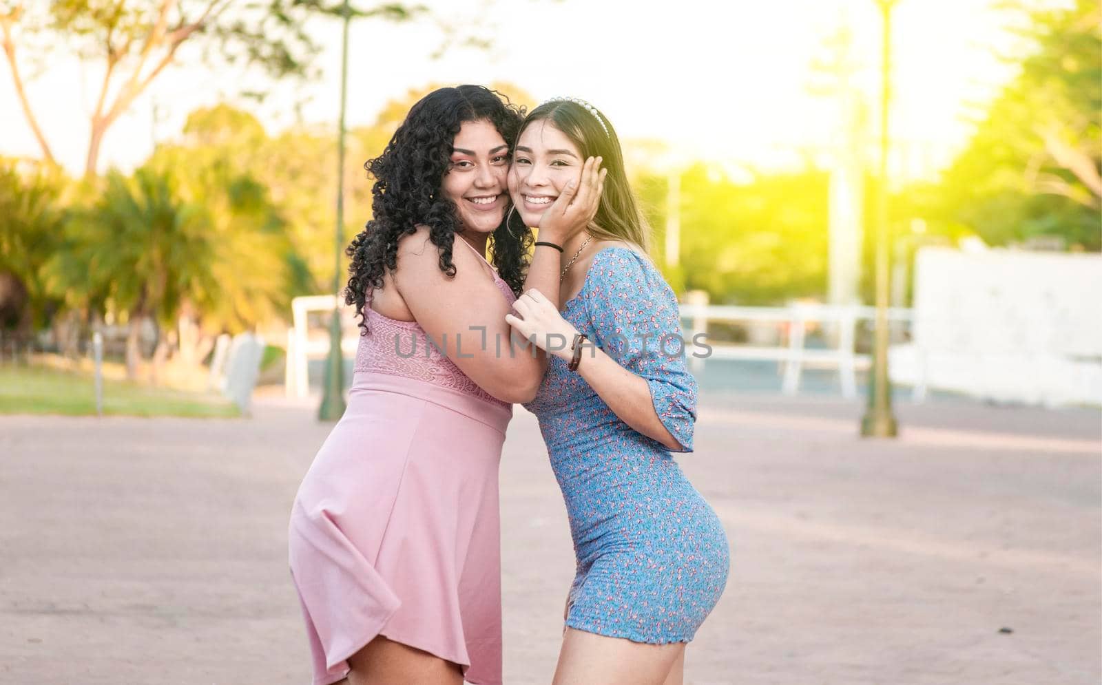 Two female friends hugging in front outdoors, girl friends hugging and enjoying life, women friendship concept by isaiphoto