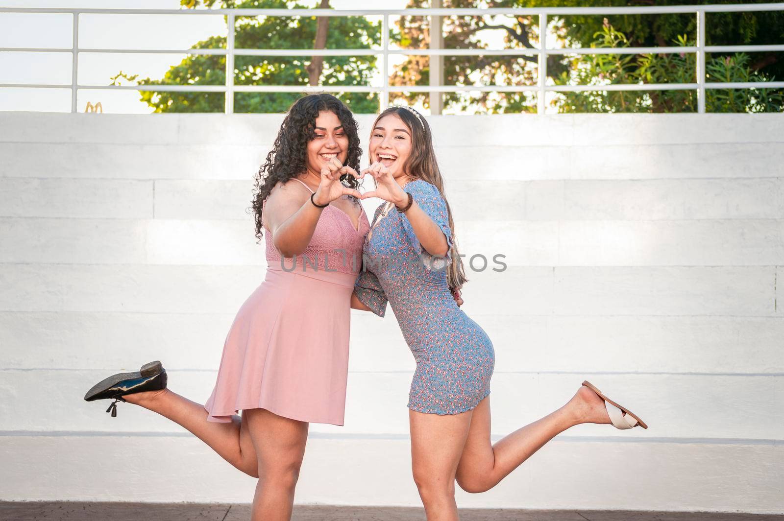 Close up of two girls making a heart shape, two friends together forming a heart, love hands sign