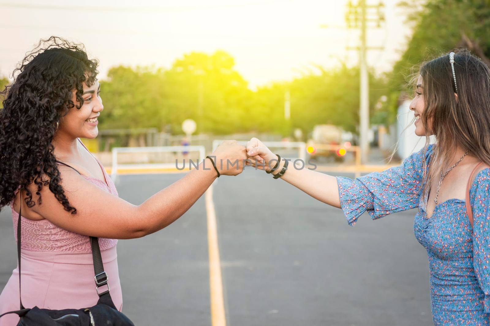 Two girls shaking fist, Two woman clashing their fists, image of two girl bumping their fists in a friendly way