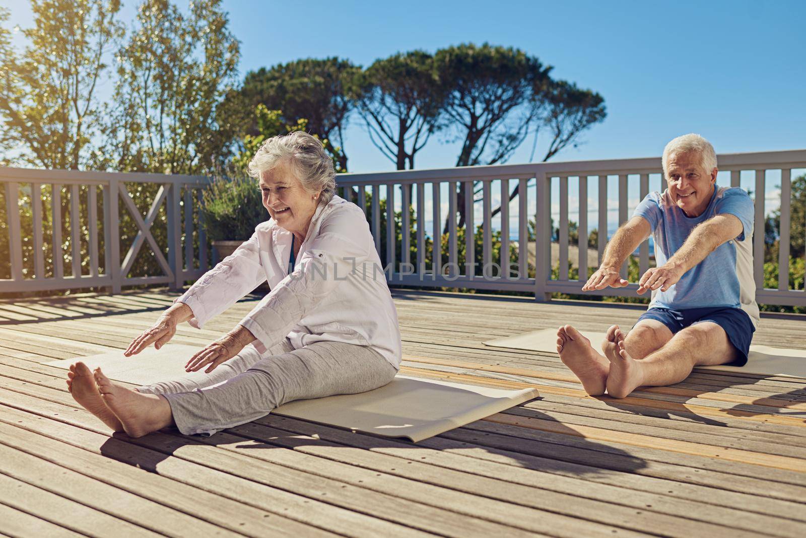 Shot of a senior couple doing yoga together on their patio outside.