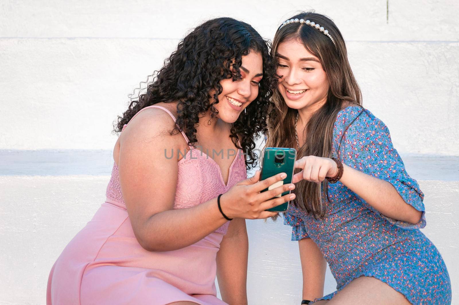 Two girls pointing at her cell phone, Girl showing her smartphone to her friend, girl checking her cell phone with her friend