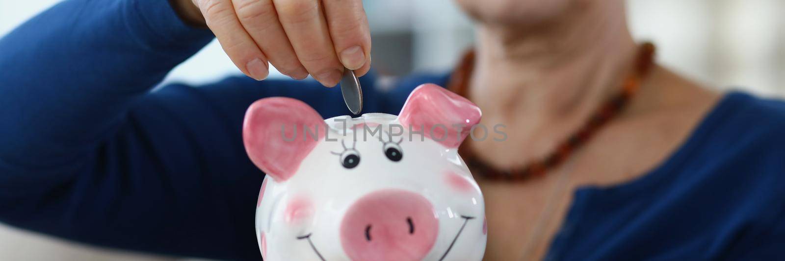 Close-up of elderly woman putting coins in piggybank. Save pension for future, collect money, take care of tomorrow. Saving up, money, finance, investment, future concept