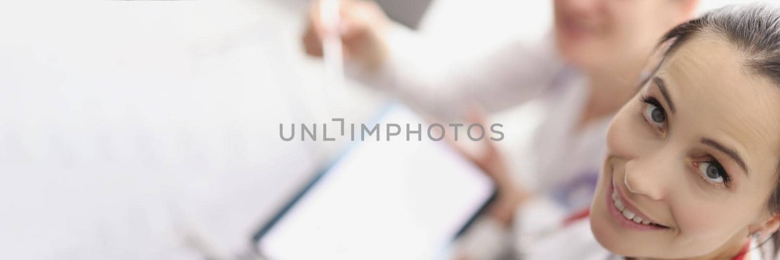 Top view of girls working in hospital spending break with tablet. Smiling nurse hold device with white screen, copy space. Pause from work, pastime, friendship, clinic concept. Blurred background