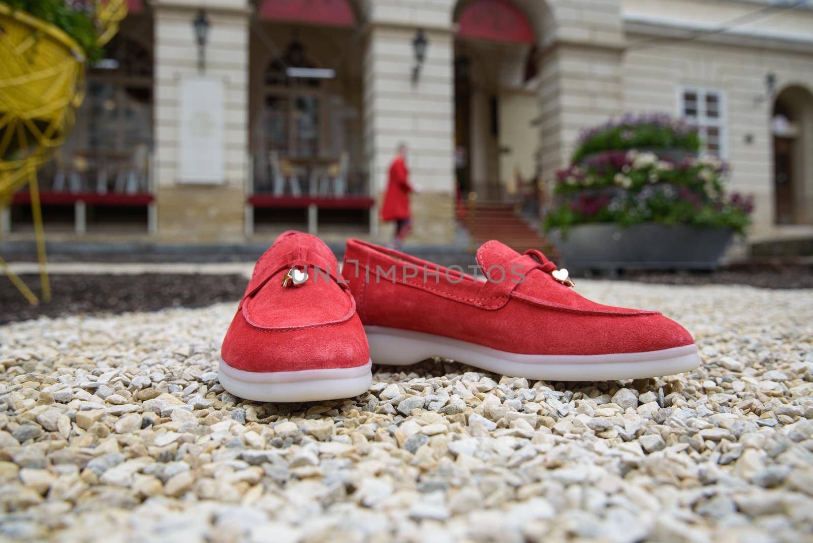 Woman's red stylish suede loafer shoes on the stone background. Pair of trendy female loafers shoes, outdoors. buildings on a background