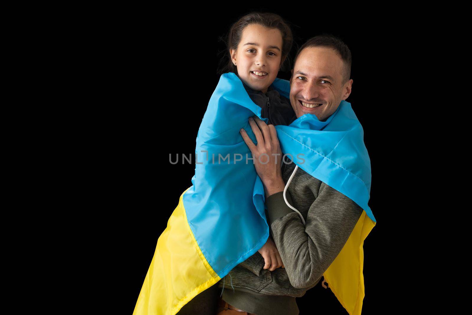 Little girl holding Ukrainian flag hugging her dad on the dark background. Stand with Ukraine. by Andelov13