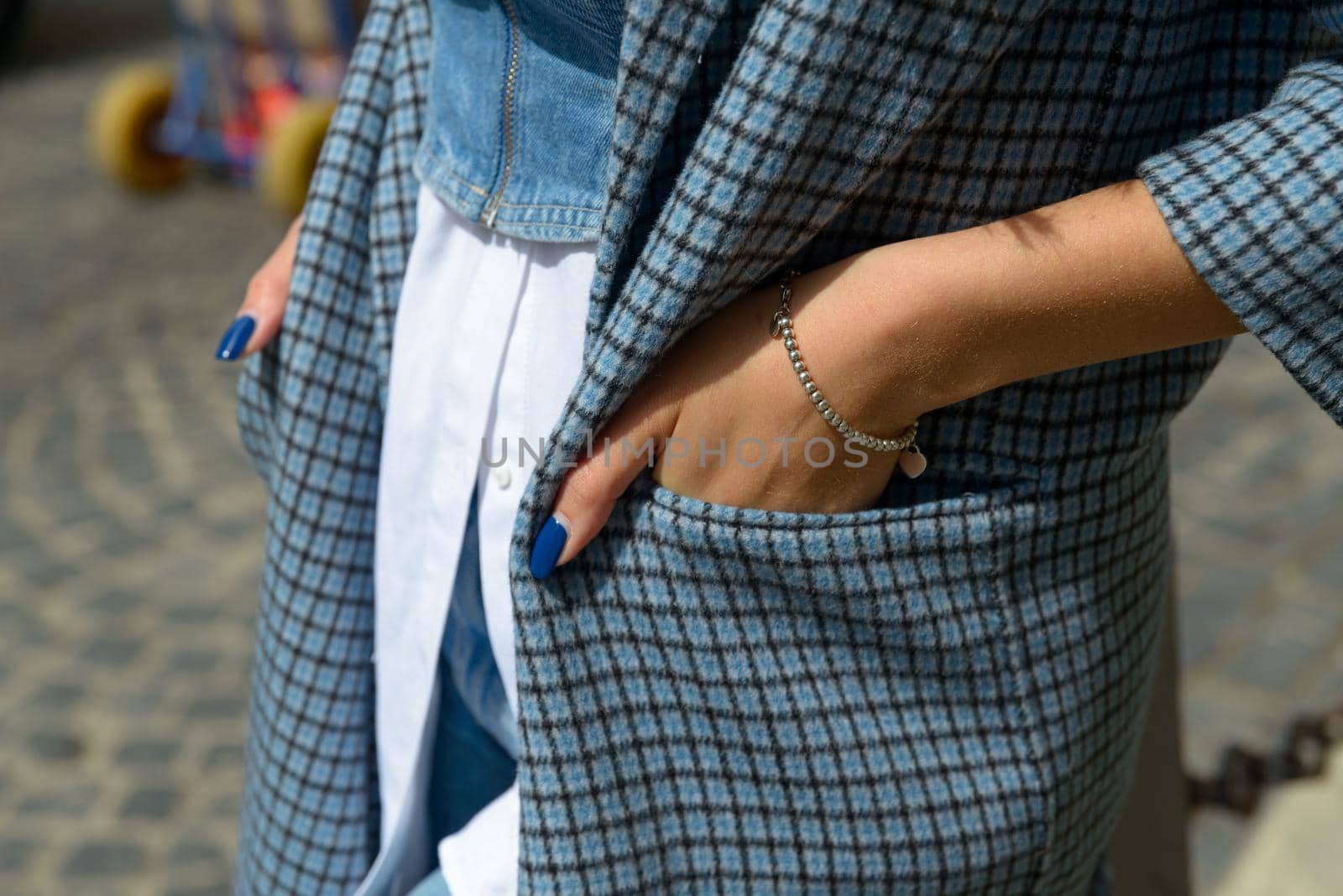 beautiful female tanned hands with blue manicure and element of stylish checkered coat