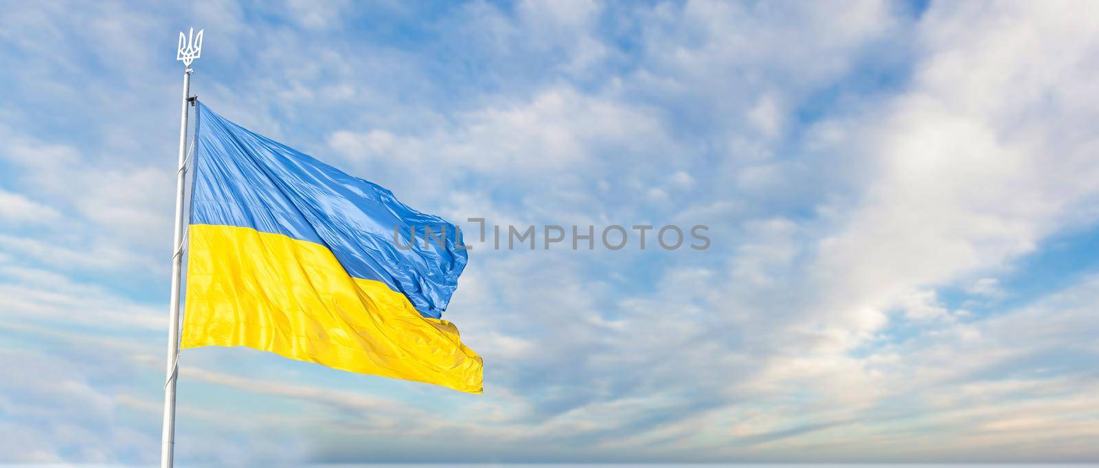 Large national flag of Ukraine flies in the blue sky. Big yellow blue Ukrainian state banner. Independence, flag, Constitution Day, National Holiday, text space. by Andelov13