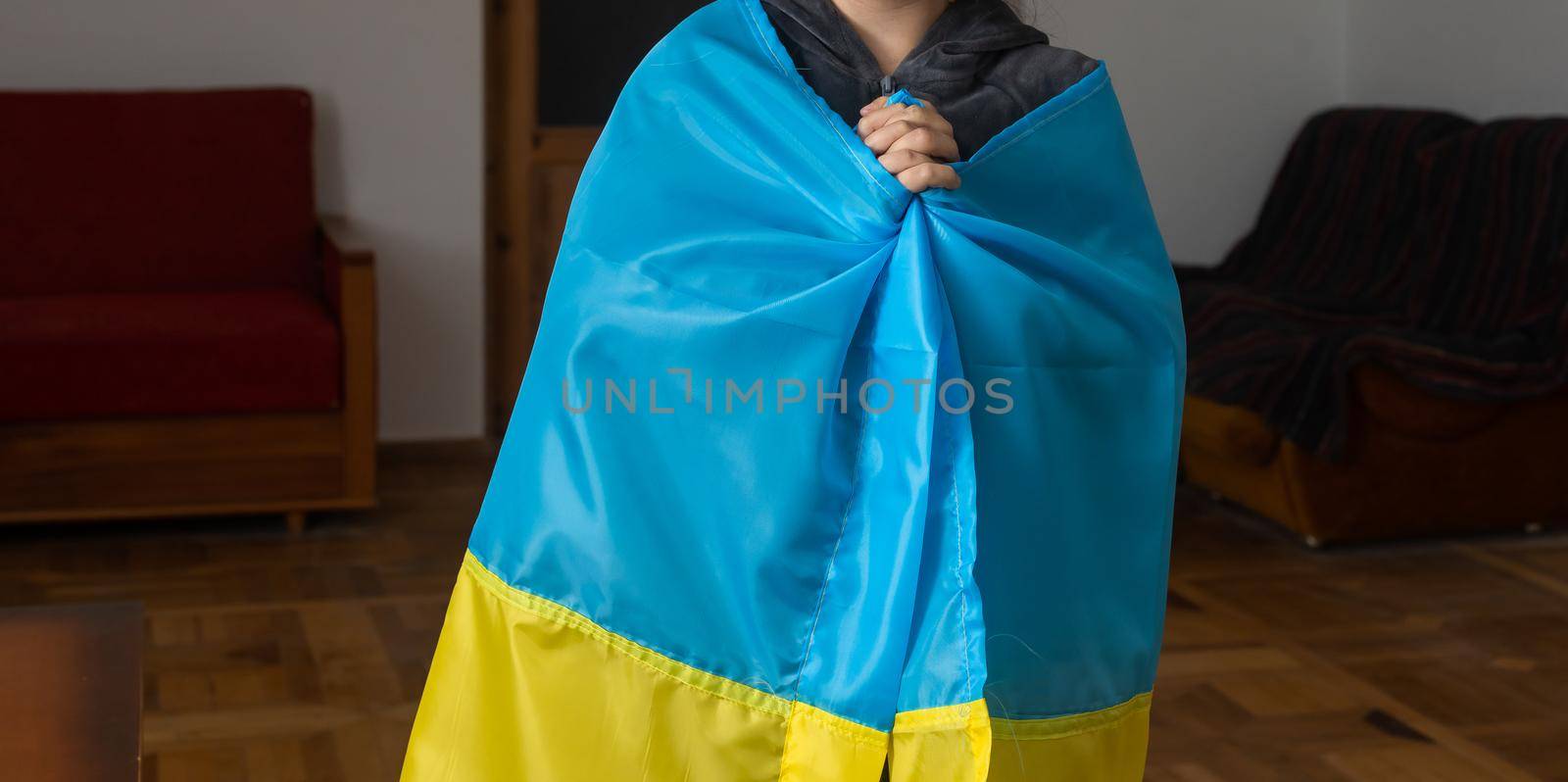 Little girls with Ukrainian flag in front of a wall destroyed from bombs. The little girls waves the national flag while praying for peace by Andelov13