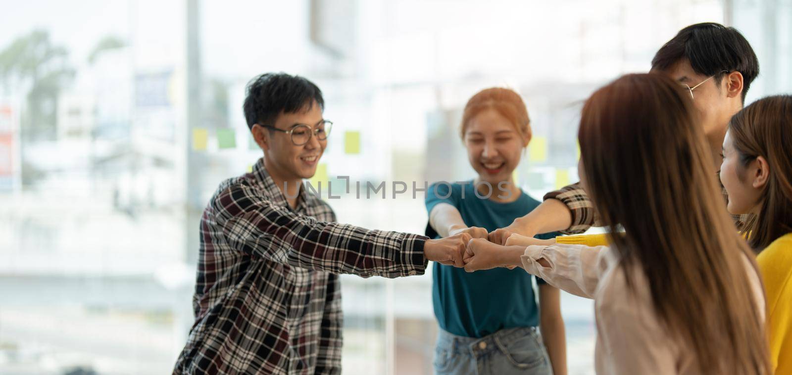diverse group of asian business partner fist bump in modern office. Colleague partnership teamwork, university student, congratulation event, job or mission accomplish concept.