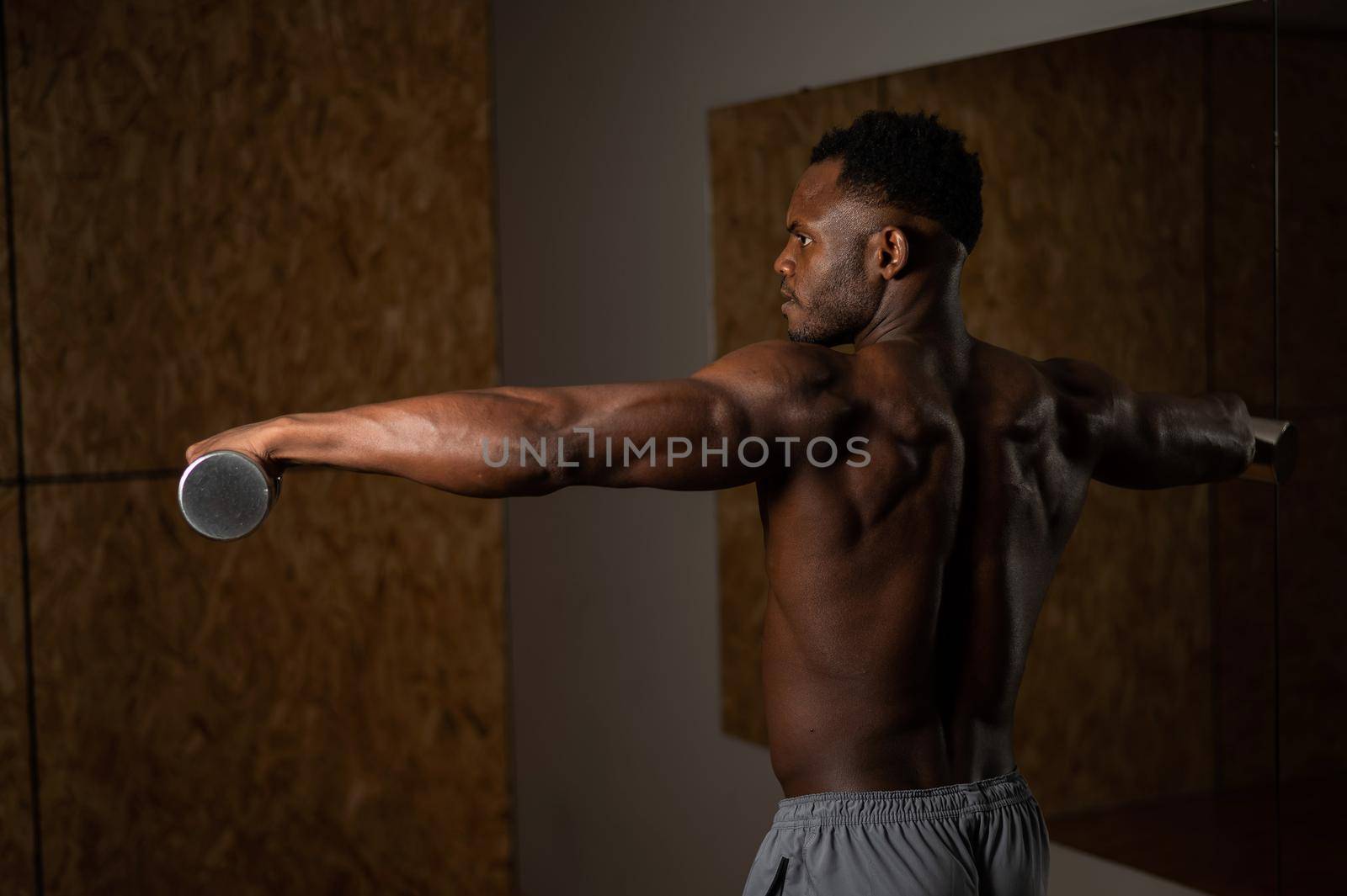 Attractive african american man doing arm exercises with dumbbells. by mrwed54