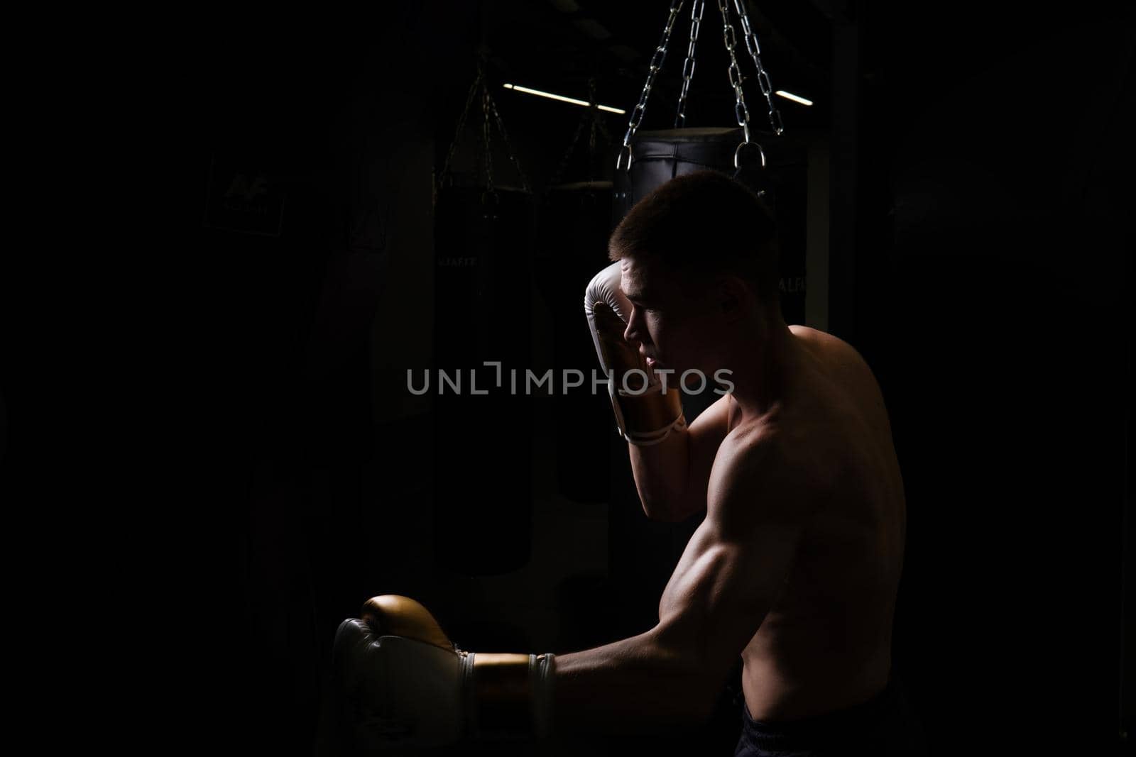 Practices athlete blows boxer the bag The glove black young male competition, for strength gloves in power and fit lifestyle, sportswear sweat. Person active dark,
