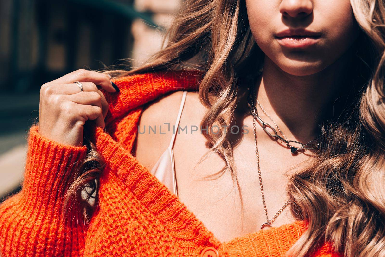 Portrait of fashionable women in orange sweater and beige dress posing in the street by Ashtray25