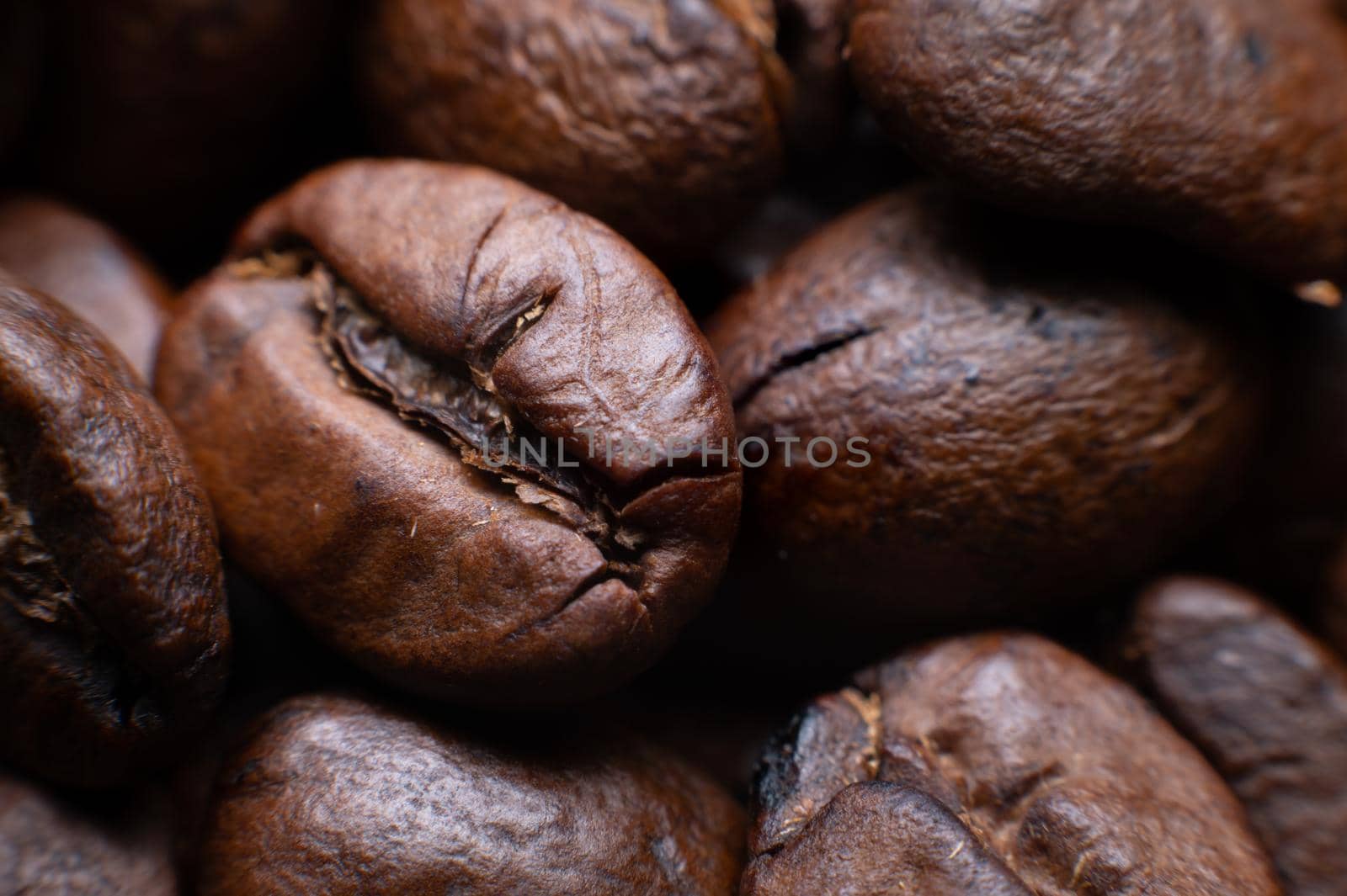 Close up extreme macro group of roasted brown or black coffee beans background in shallow depth of field. Enchanting coffee aroma.