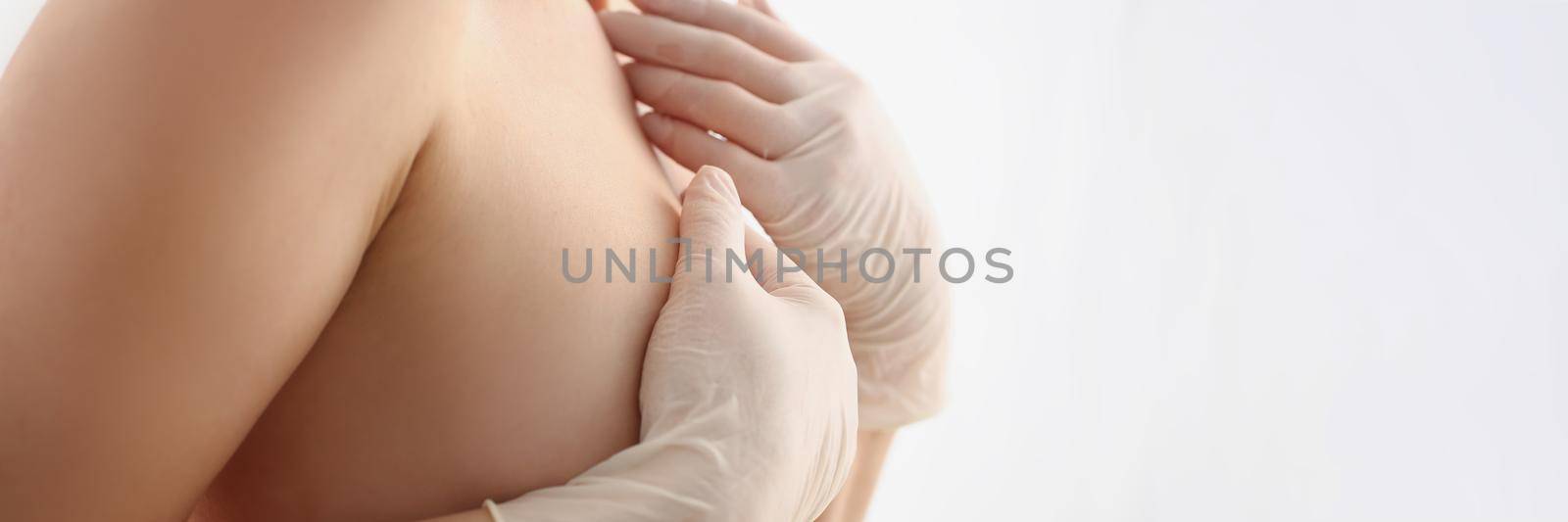Close-up of topless woman standing sideways, cover naked breasts with hand. Analysis and diagnostics before breast augmentation procedure. Medicine, beauty, plastic concept. White background