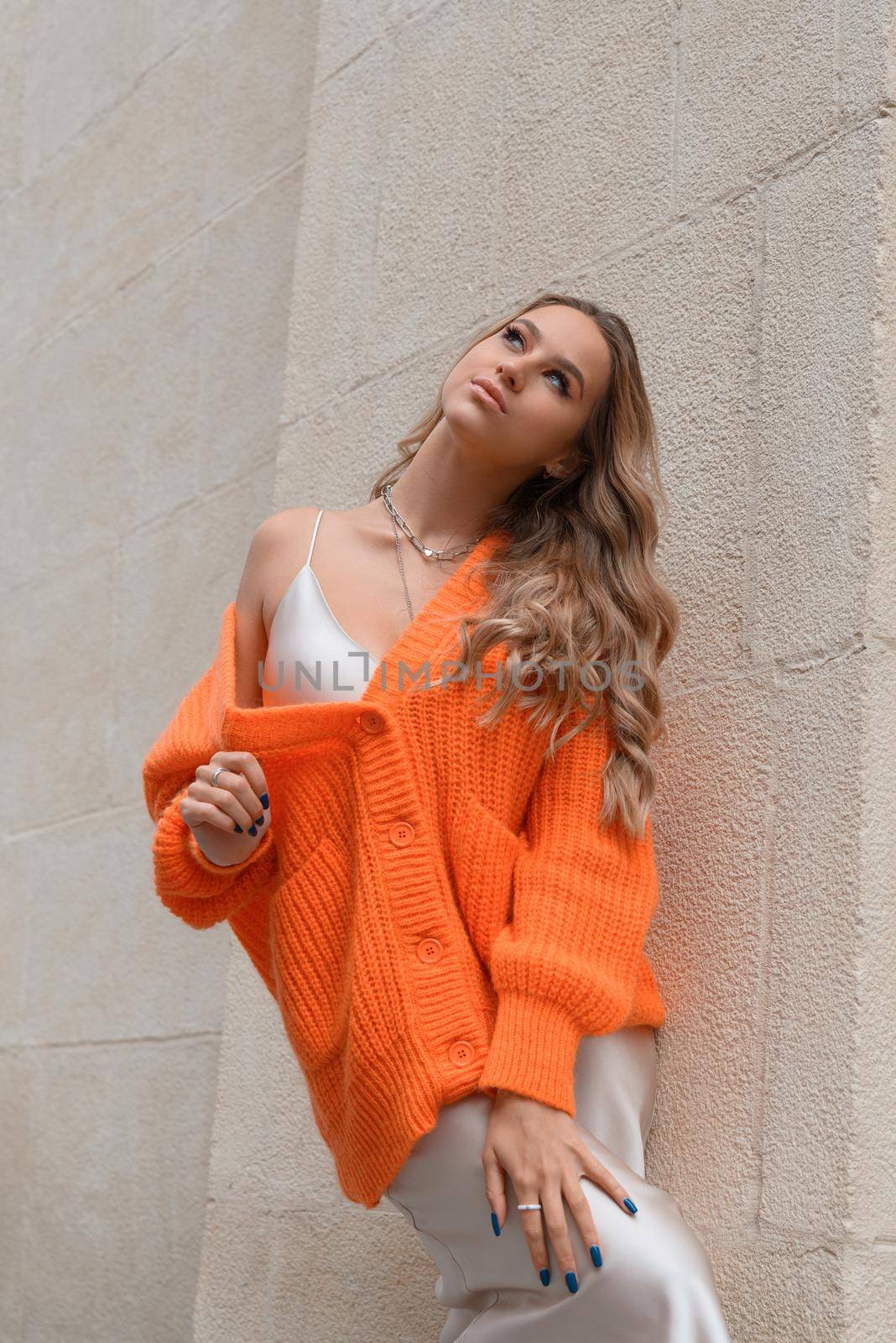 Portrait of fashionable blond women in orange sweater and beige sweater posing in the street