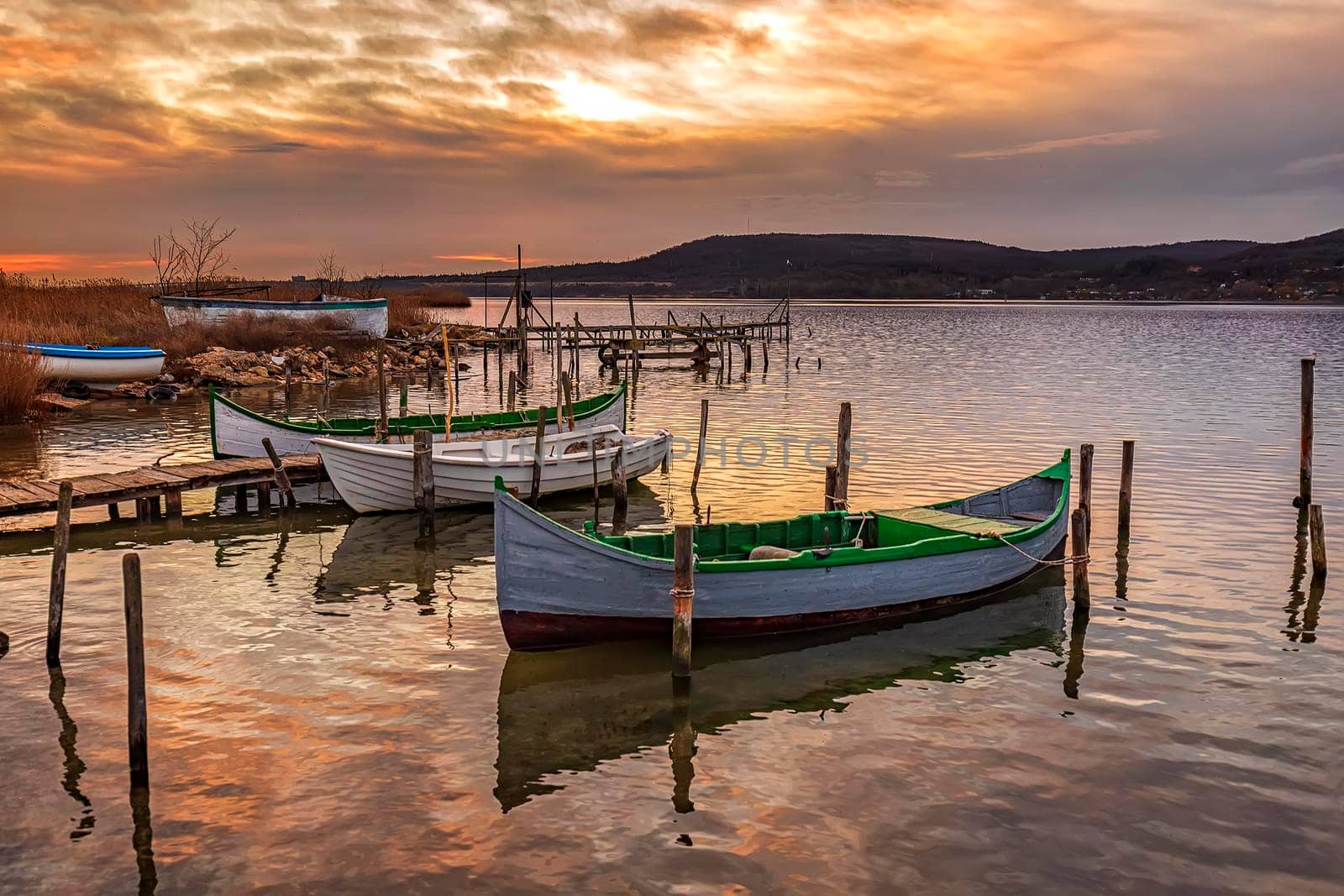 The tranquil afternoon on a lake with moored boats at wooden pier  by EdVal