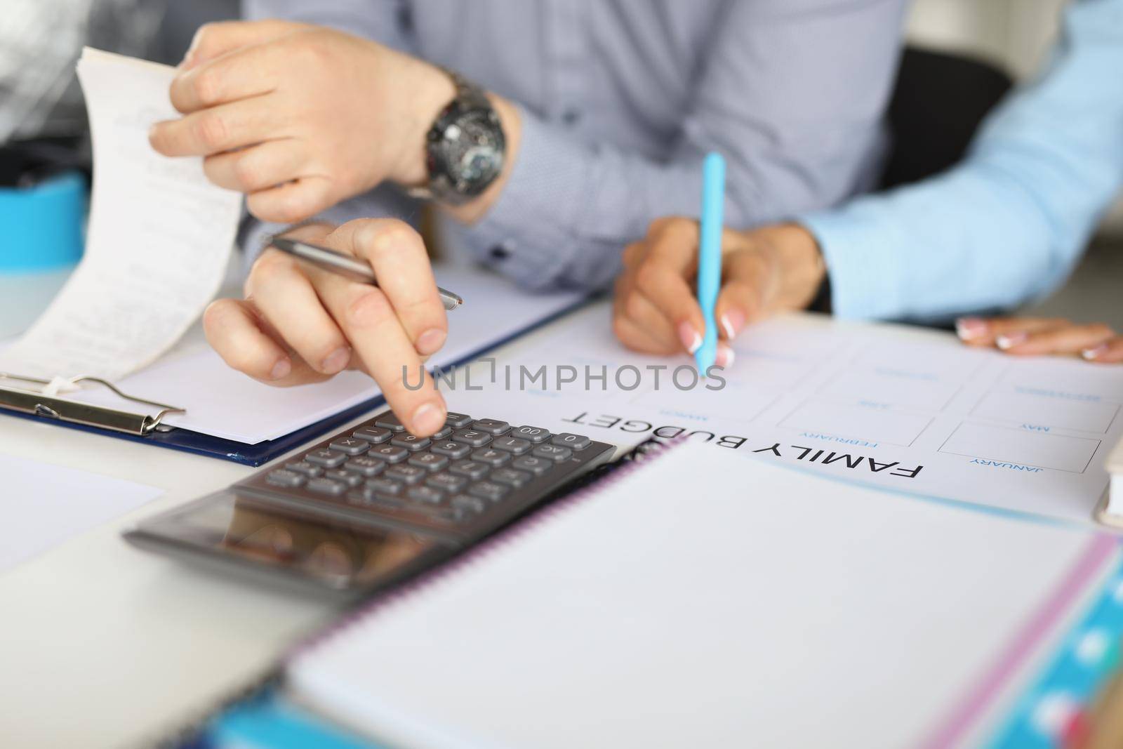 Close-up of couple planning family budget for month. Man counting on calculator, woman write down on paper expenses. Income, saveup, finance, economy, money concept