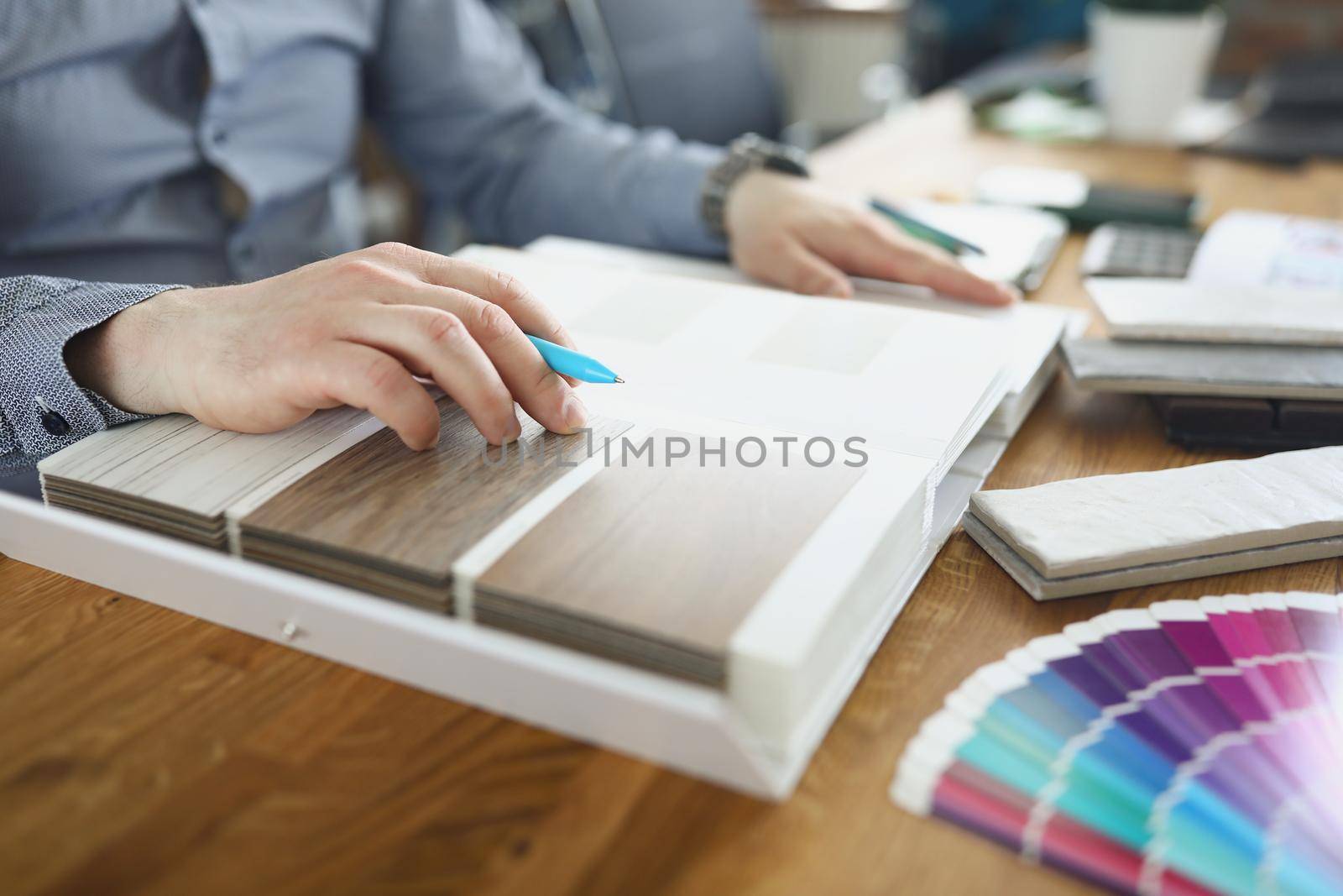 Close-up of interior designer man choosing floor cover for client, colourful palette. Selection of material color from samples. Architect, designer, creative, art, renovation concept