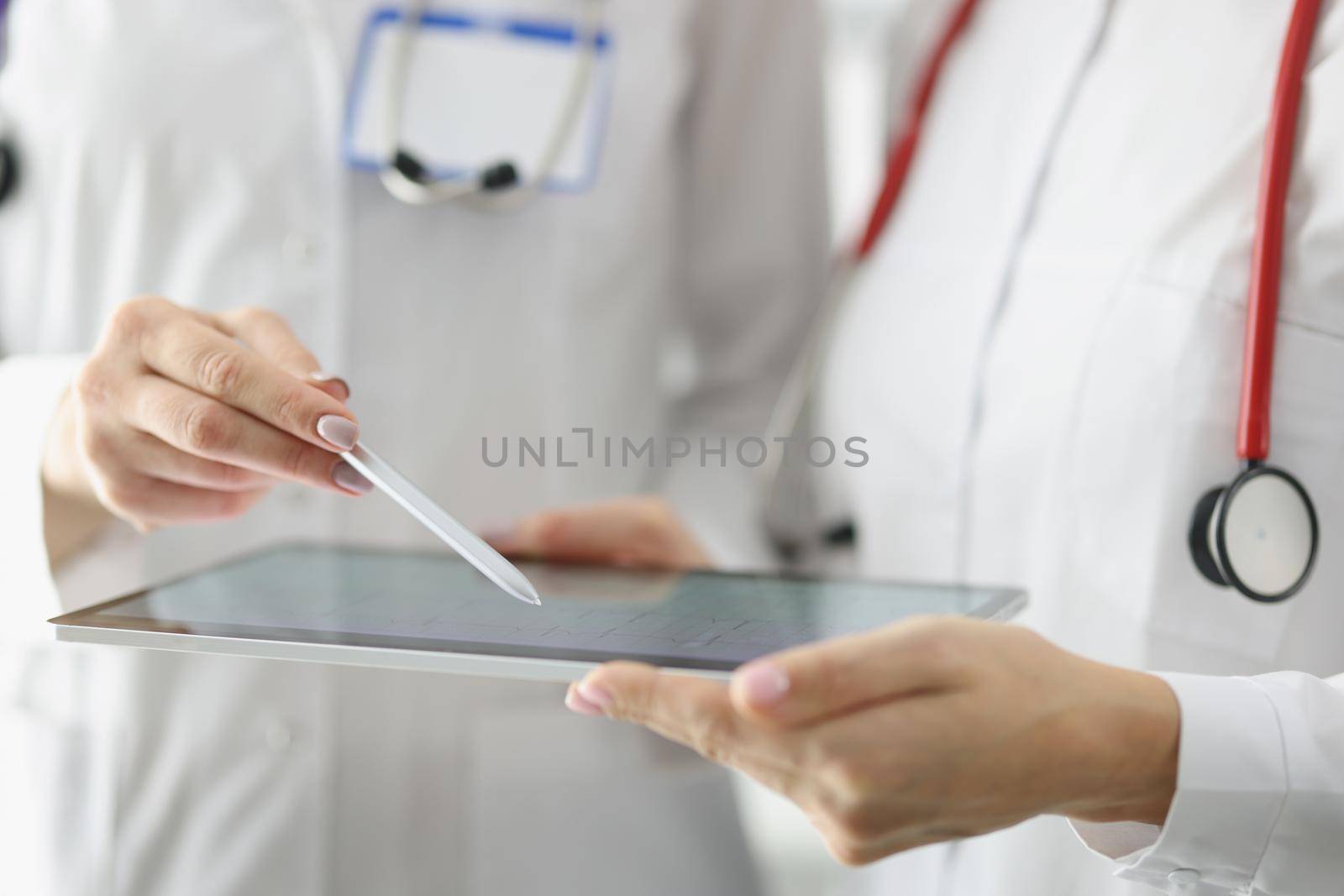 Close-up of doctor point with pen on tablet screen, result of echocardiogram on device. Professional medical worker discuss treatment. Medicine, checkup, cardiology, health concept. Blurred background