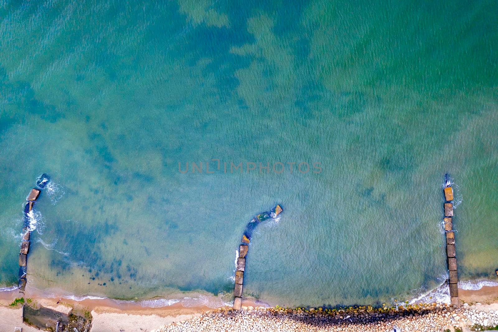 Aerial top view from drone to the seacoast and old concrete piers. Sea background.