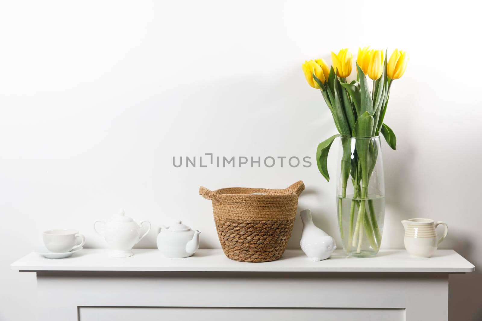 Bouquet of yellow tulip in the glass vase on white table