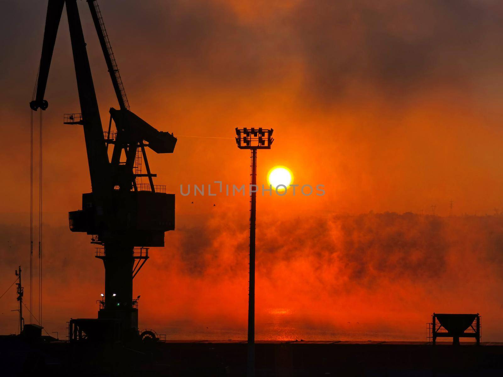 Silhouette of the port crane at amazing red sunrise. Horizontal view by EdVal