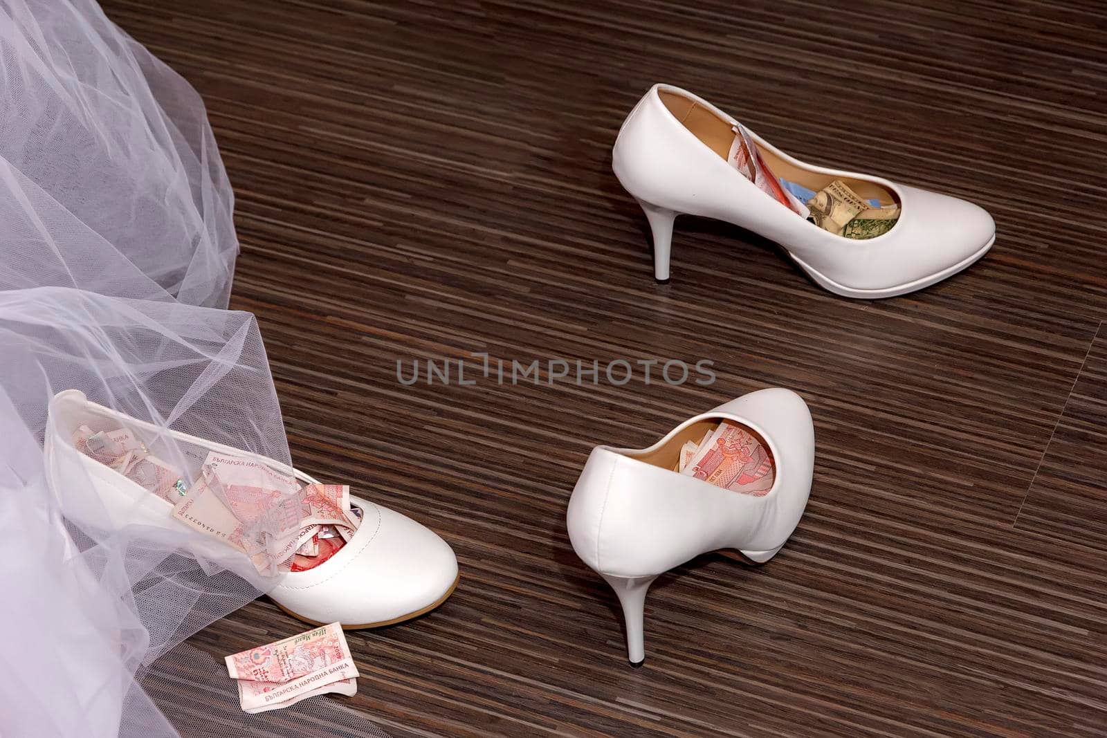 a white wedding shoes full of money and currency. ritual at some weddings-the shoe is filled with money then the bride is given to the groom. by EdVal