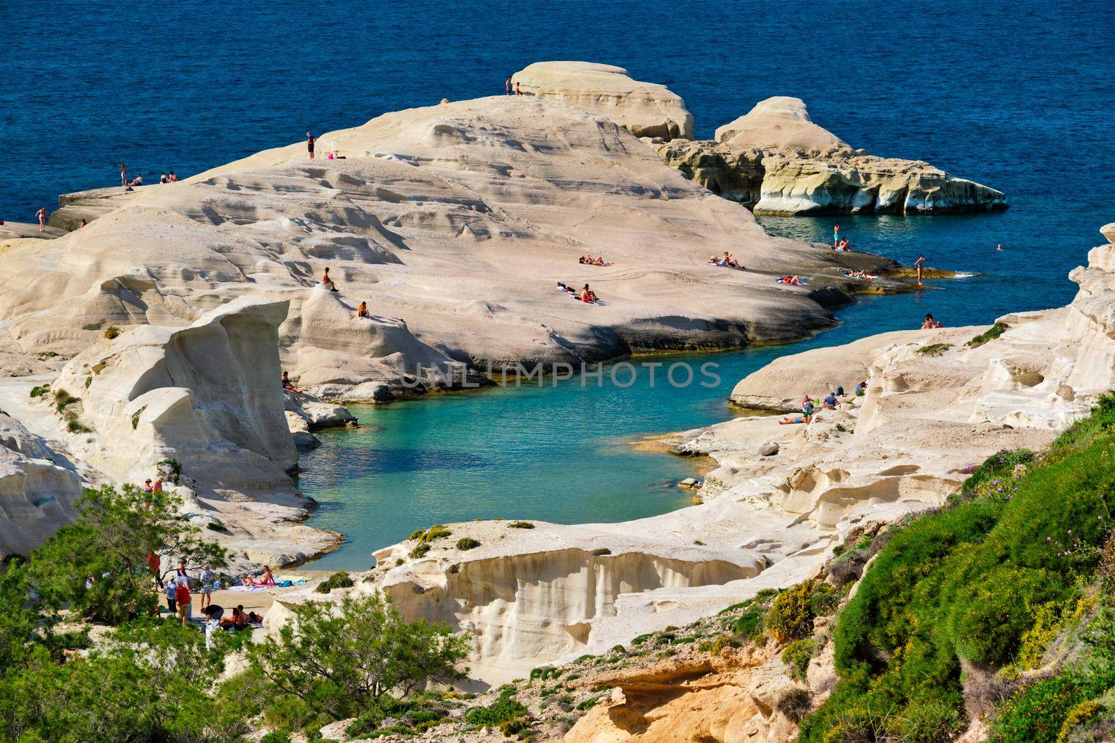 White rocks of famous tourist attraction of Milos island Sarakiniko beach with tourist relax and Aegean sea, Milos island , Greece