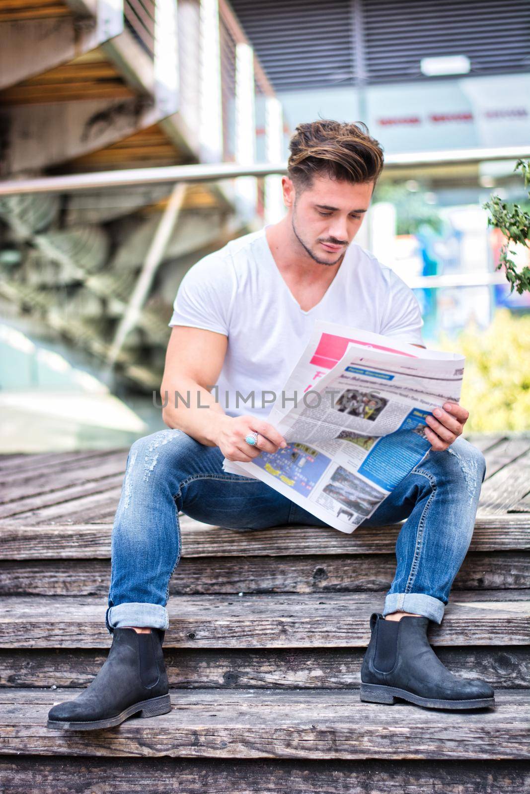 Handsome man reading newspaper outdoor in city by artofphoto