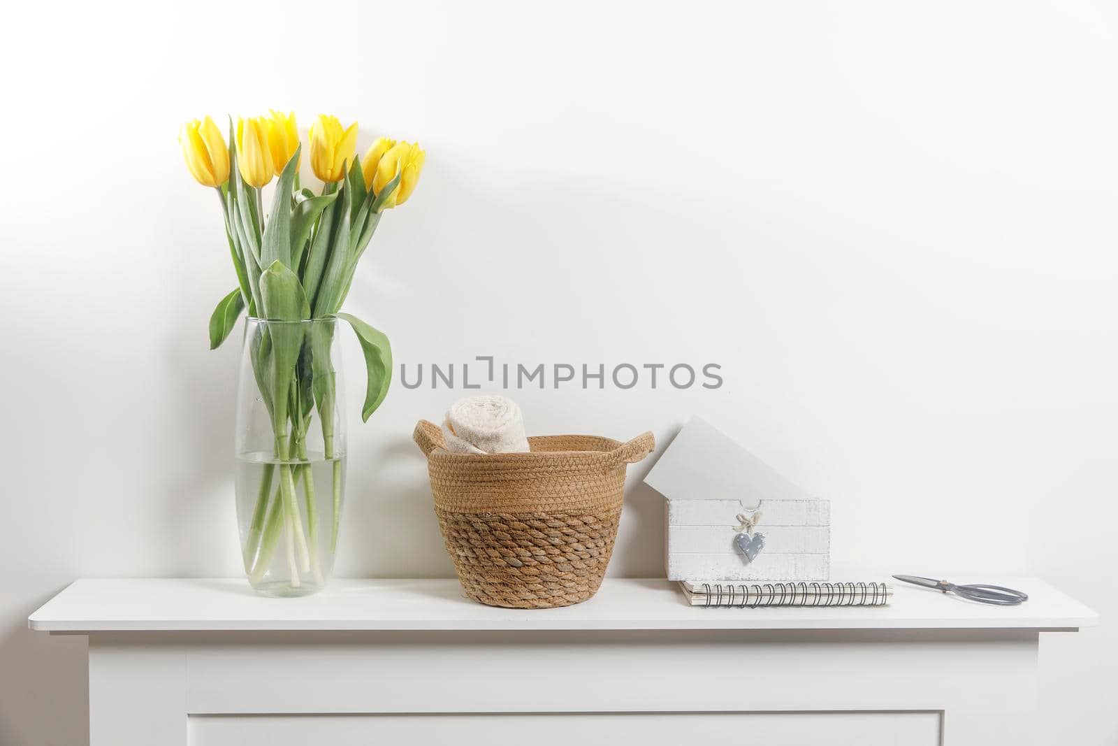 Bouquet of yellow tulip in the glass vase on white table by elenarostunova