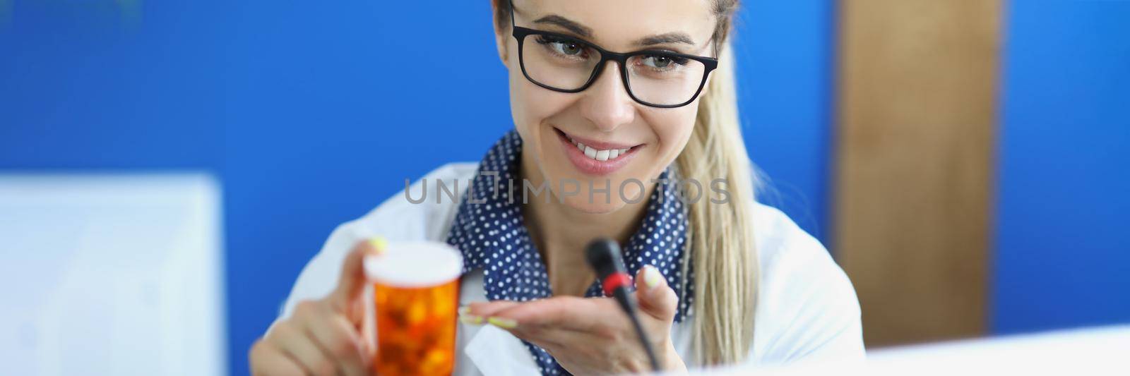 Portrait of female doctor in uniform holding container with medication. Qualified specialist advertises drug for treatment. Medicine, pharmacy, hospital, prescription