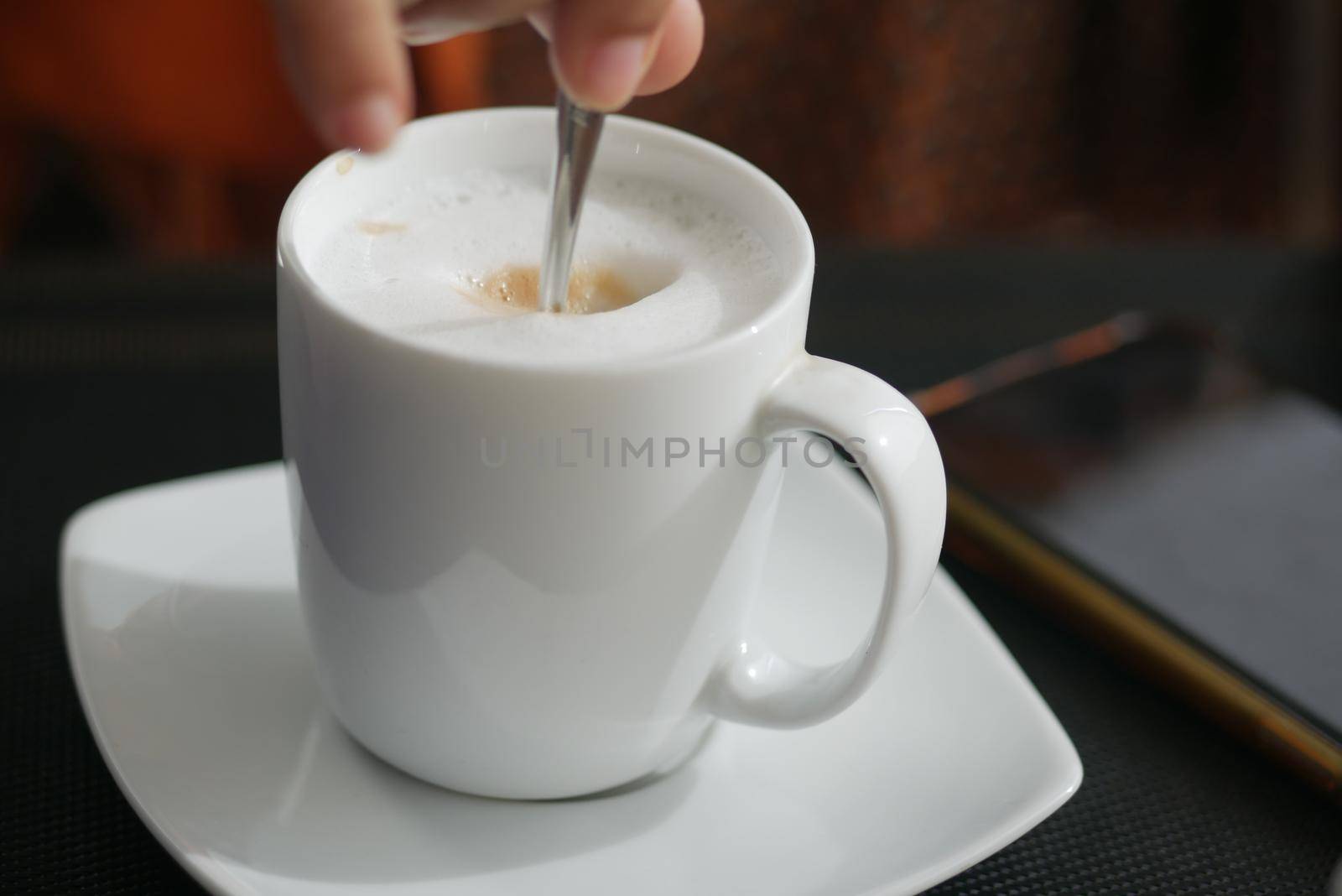 person hand stirring coffee with spoon
