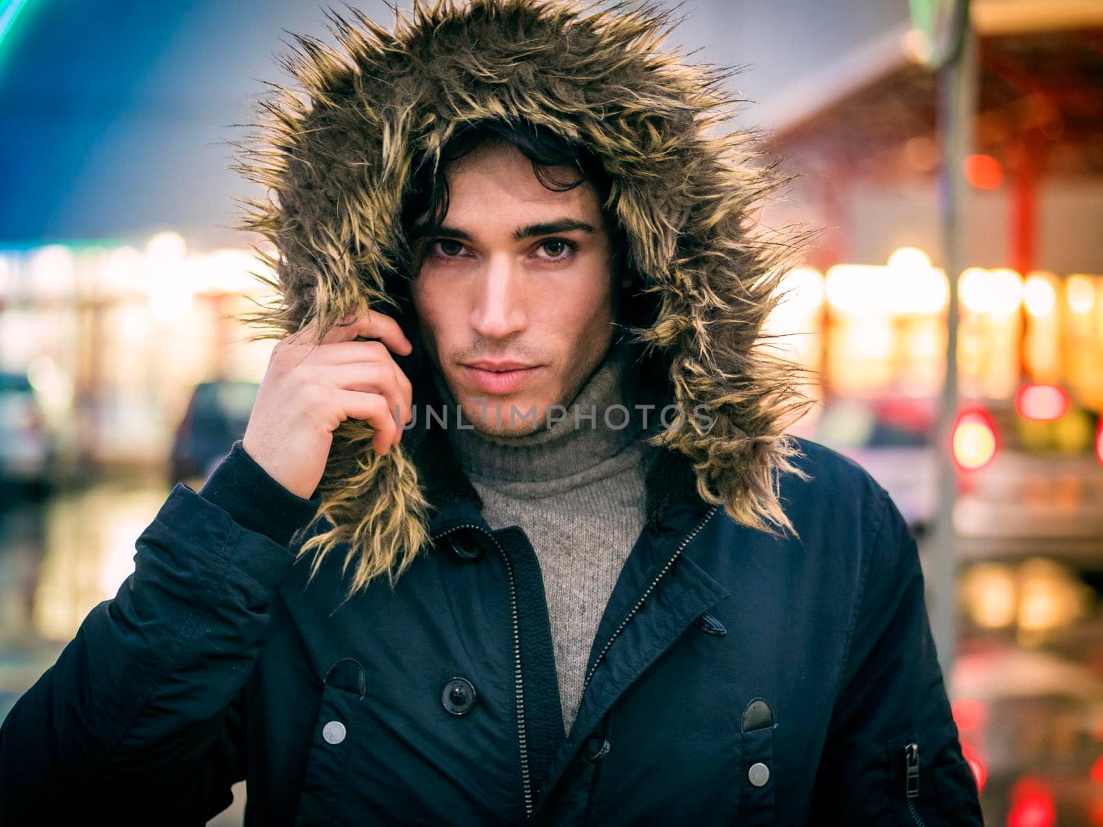 Full length of young man in coat walking under rain along the city street