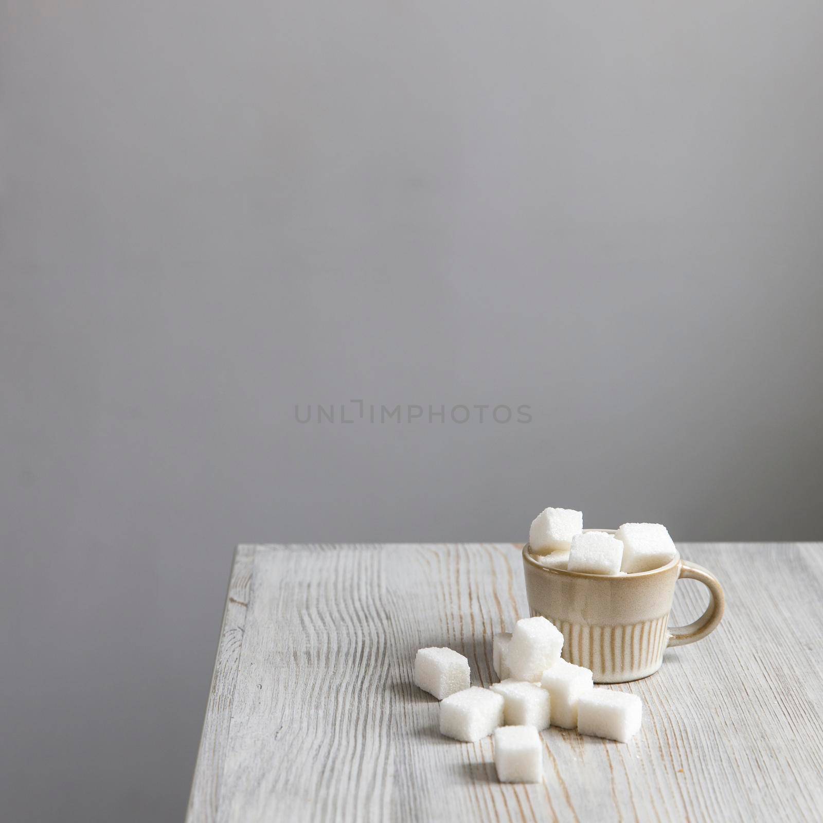 Cup with refined sugar in pieces scattered on the table